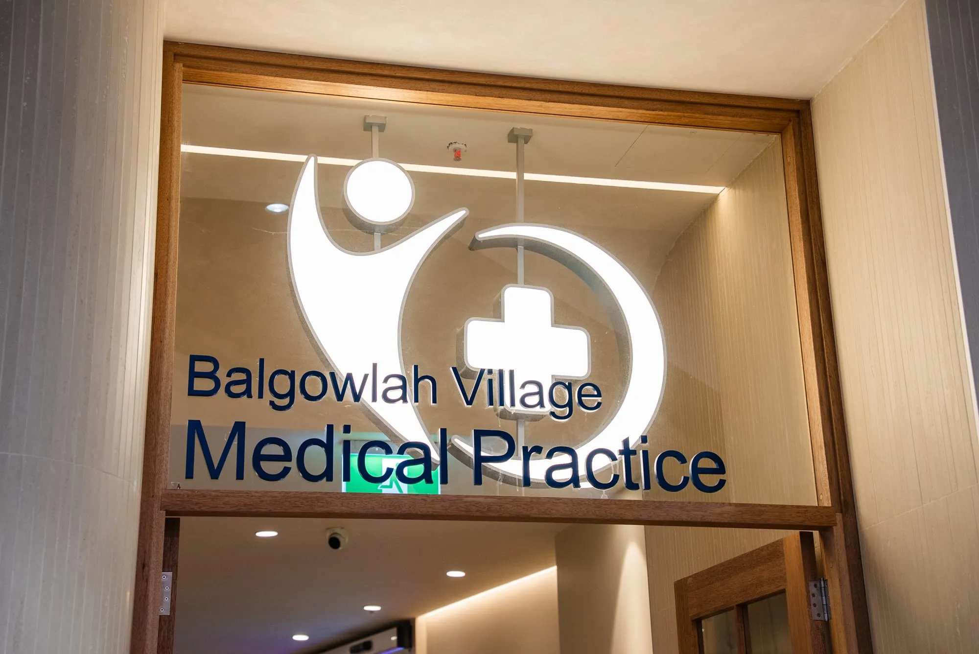Backlit medical practice signage set into a timber feature wall