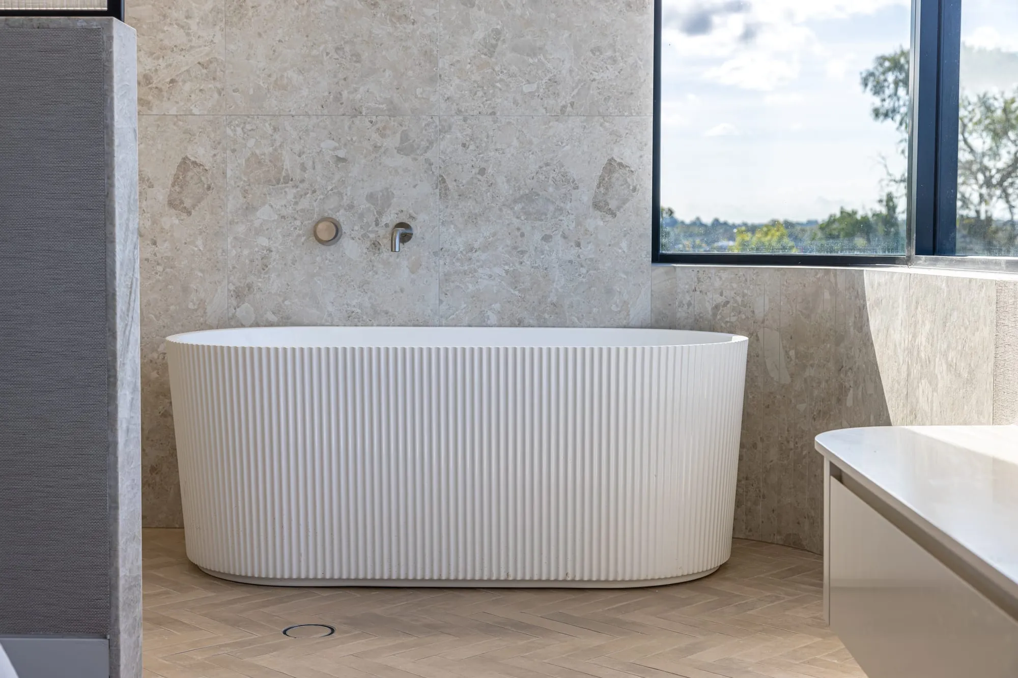 Freestanding stone bath set against a picture window