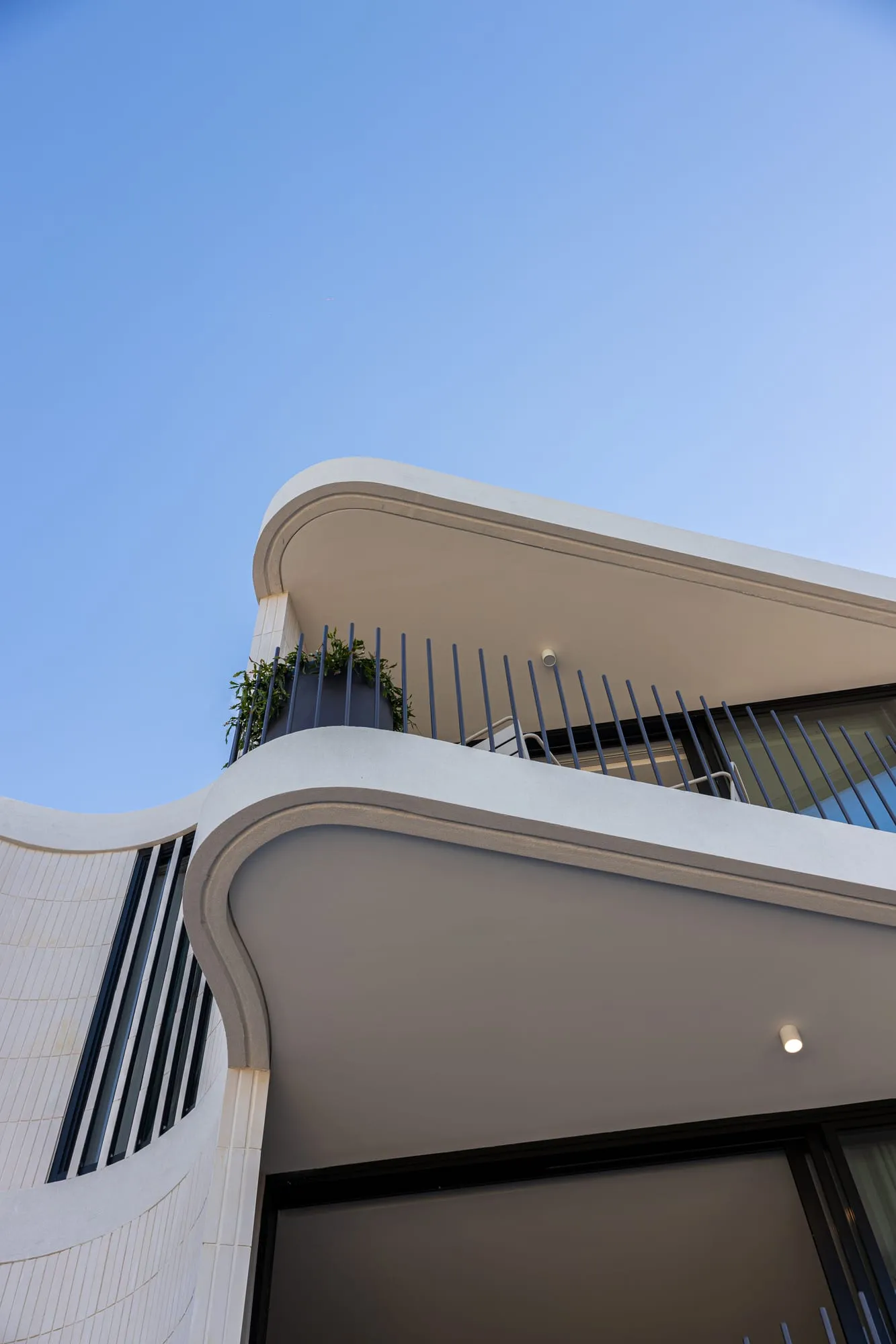 Curved rendered facade and cantilevered balcony of the Sylvania custom home
