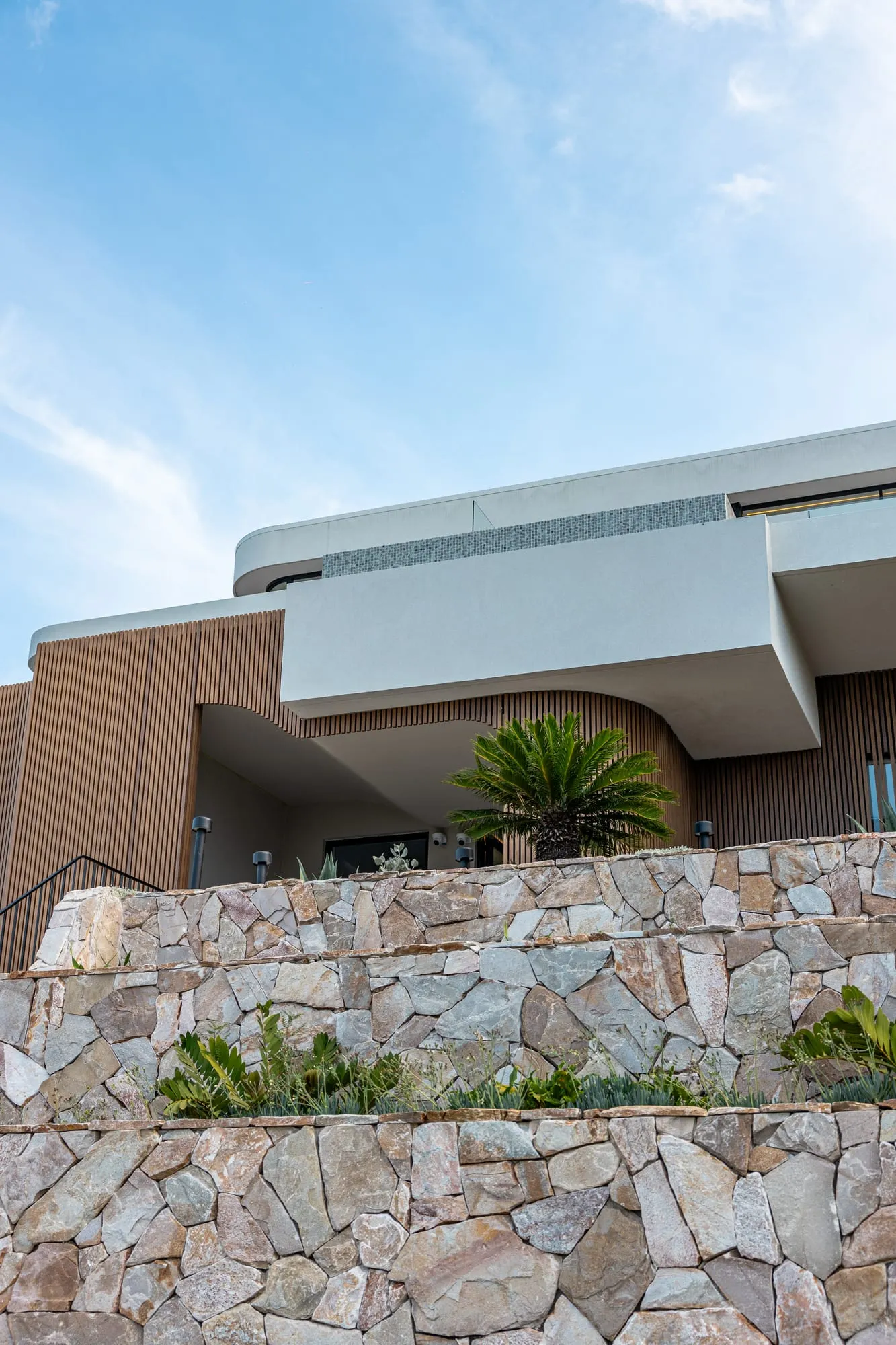 Curved facade and natural-stone base of the Yowie Bay home