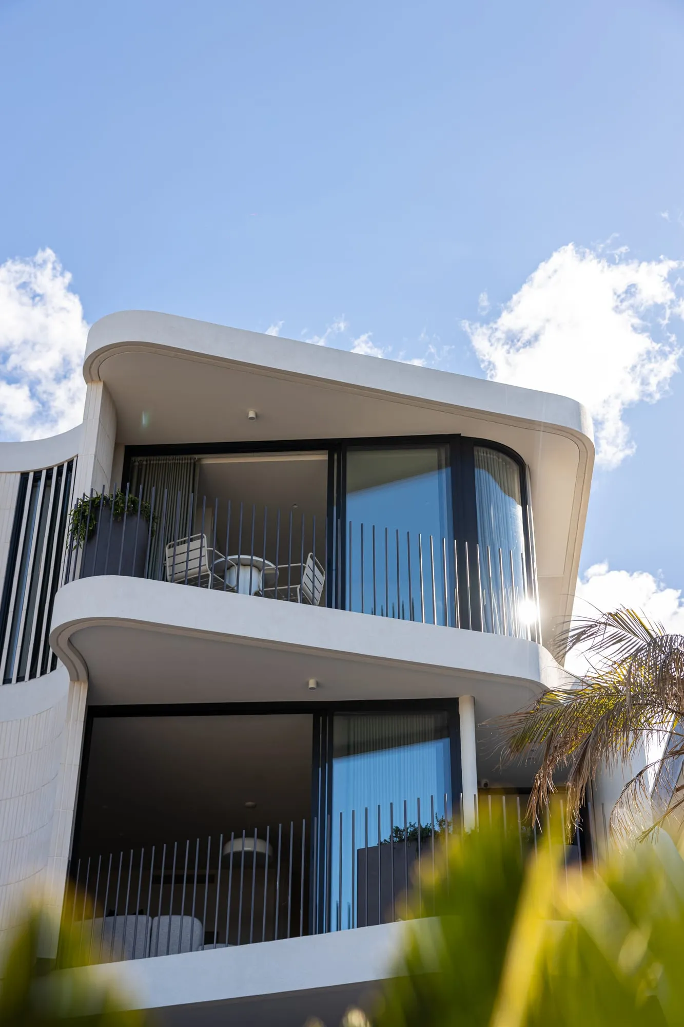 Sculptural curved white facade of a new custom home in Sylvania against a blue sky