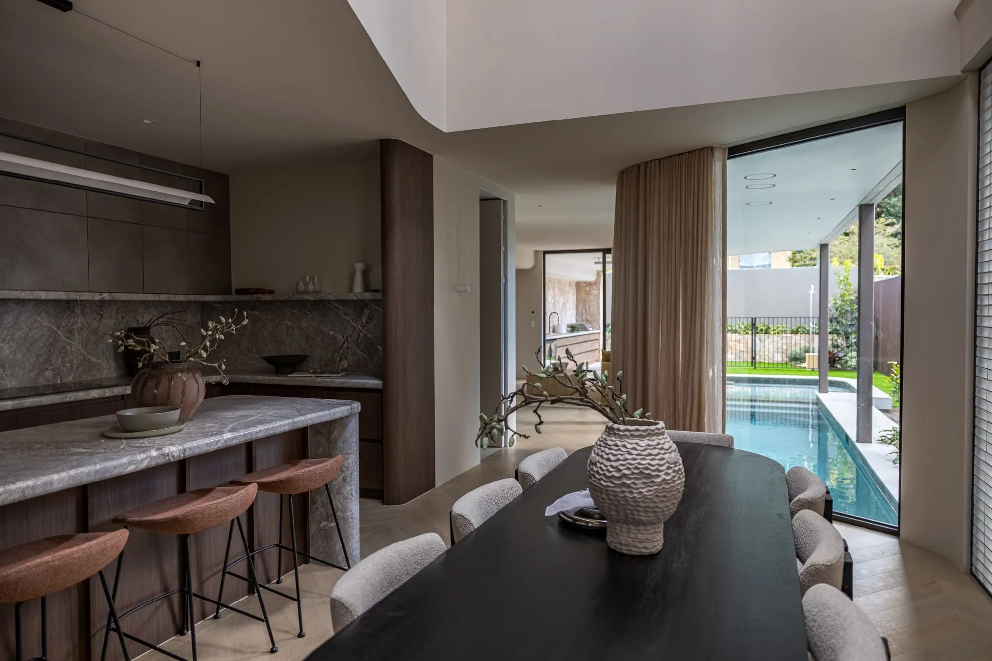 Open-plan kitchen with a natural stone island bench overlooking the pool