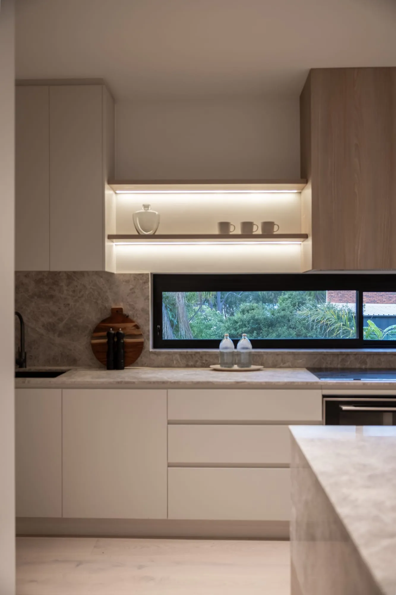 Kitchen with a window splashback framing greenery