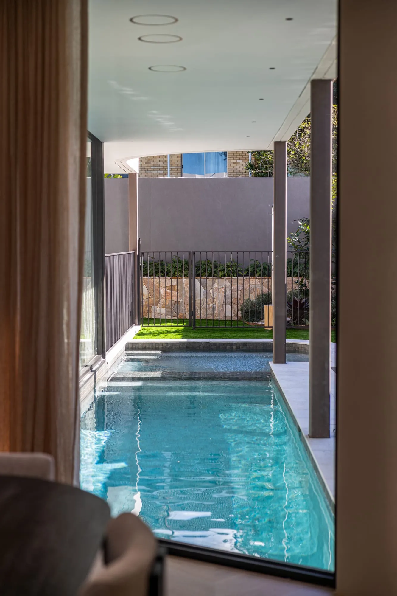 Living space framing the lap pool beyond floor-to-ceiling glass