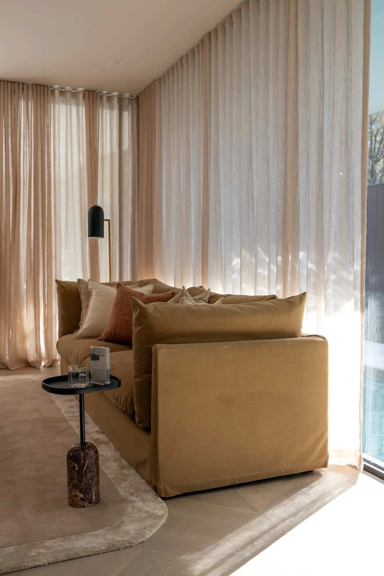 Detail of an olive-toned lounge framed by sheer curtains