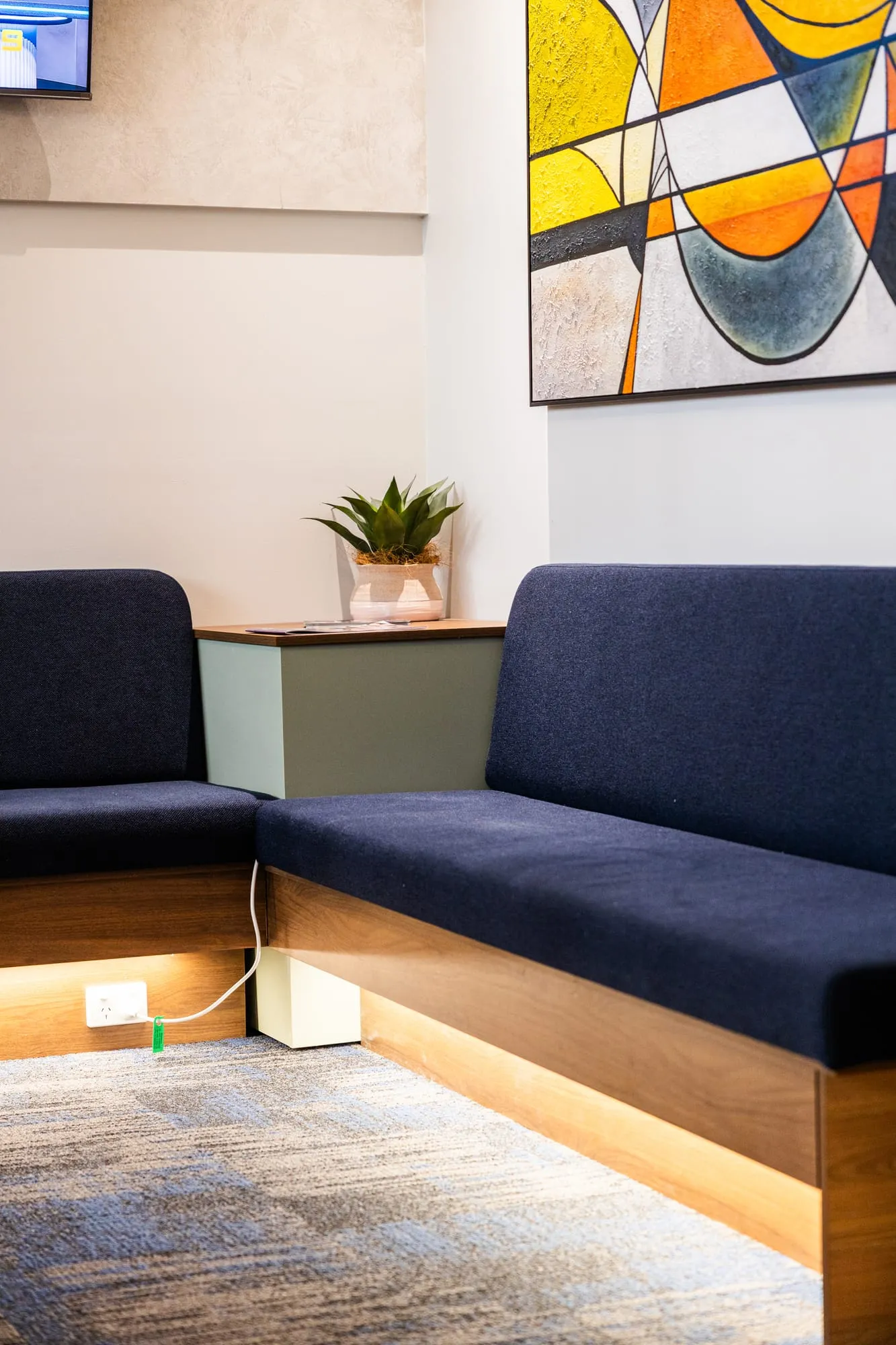 Waiting nook with navy seating and bright abstract artwork