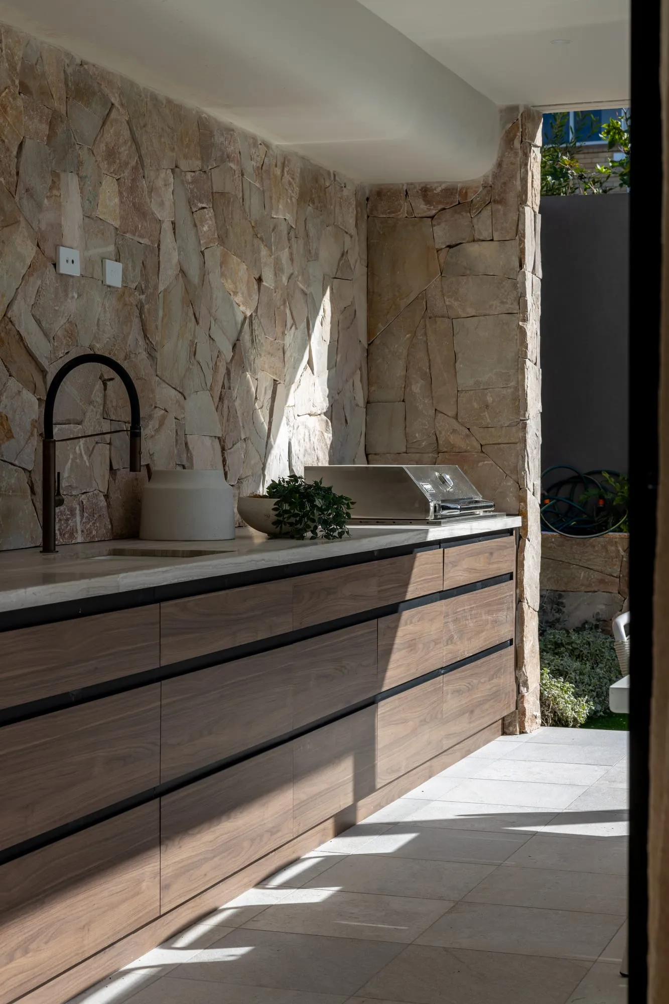 Alfresco outdoor kitchen with a natural stone feature wall