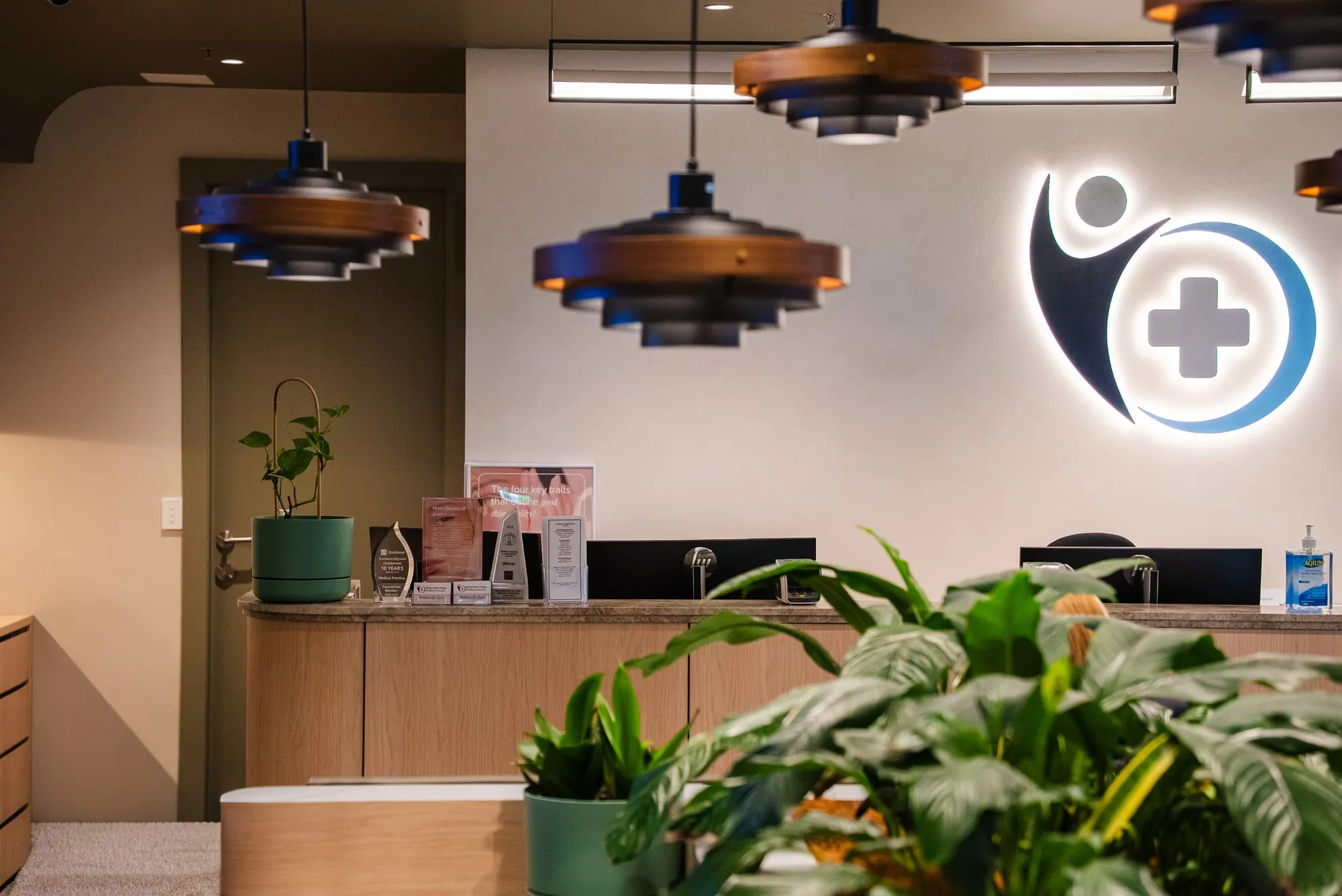 Medical practice reception framed by planters and pendant lighting