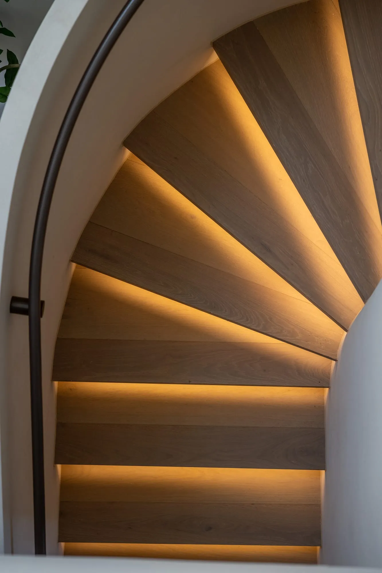 Curved timber staircase with warm concealed lighting