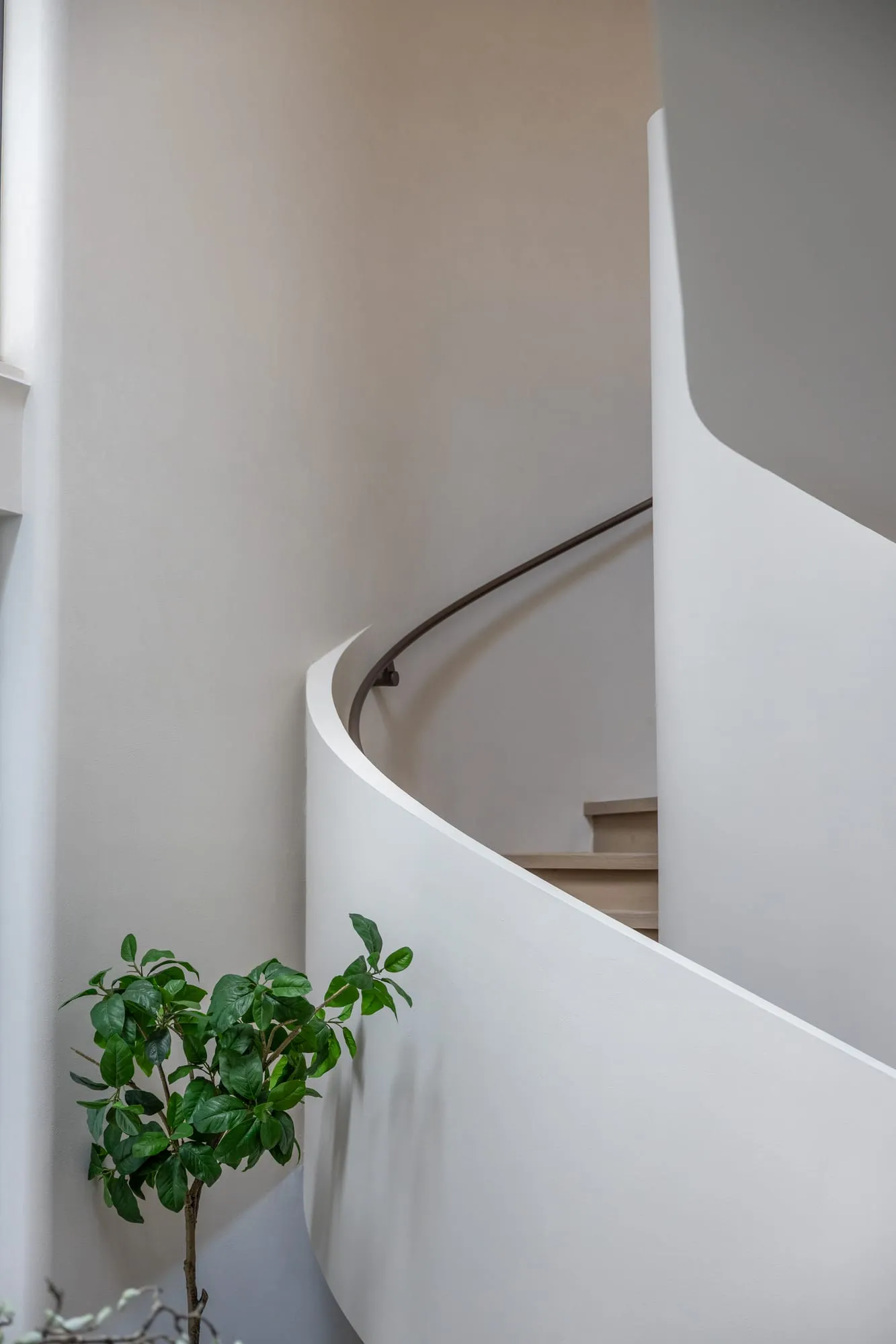 Sculptural curved staircase rising through a double-height void