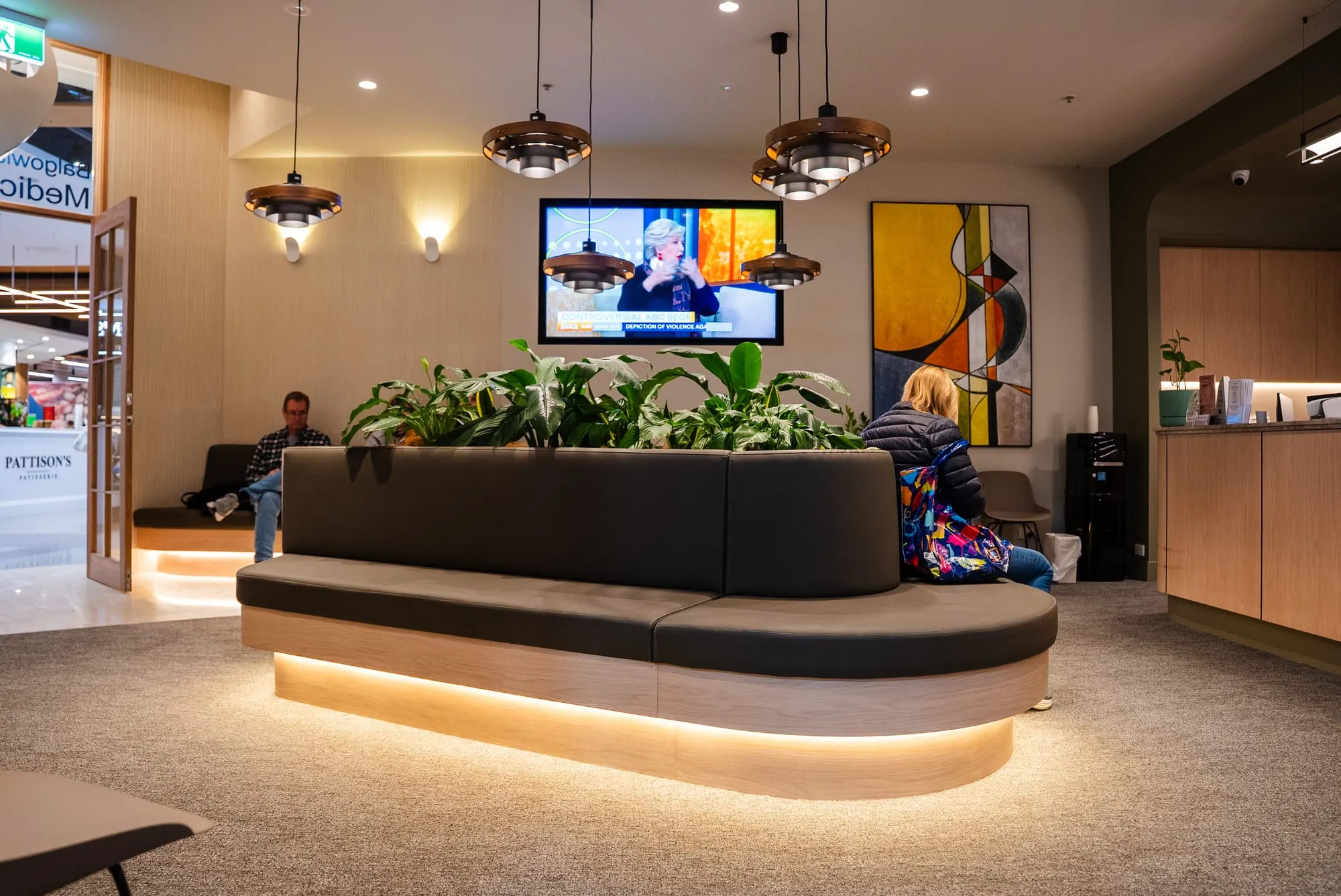 Waiting area with a curved upholstered bench and warm concealed lighting
