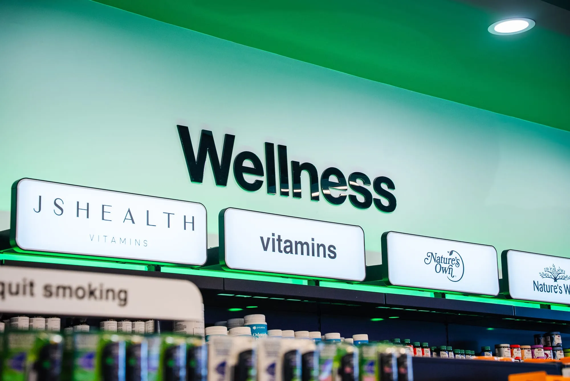 Backlit wellness and vitamins signage over fitted shelving